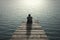 Businessman sitting and thinking on old wooden pier to the sea