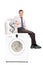 Businessman sitting on washing machine full of money