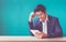 Businessman sitting at wood table and green wall and looking dow