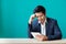 Businessman sitting at wood table and green wall and looking dow