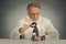 Businessman skeptically looking at small employee through magnifying glass