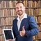 Businessman smiling presenting on tablet in library