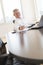 Businessman Smiling While Writing On Document At Desk