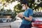 Businessman standing on the car and check mobile phone for business. Wearing a face mask to protect against coronavirus