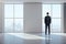 Businessman standing in exhibition interior and looking to city