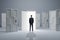 Businessman standing in front of abstract white puzzle door in interior. Future, choice, success, direction, opportunity and