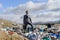 Businessman standing on landfill, large pile of waste. Consumerism versus pollution concept. Corporate social