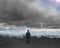 Businessman standing toward waves and cludy sky with Lightning ,