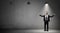 A businessman stands on concrete background under the light of a single working industrial lamp.