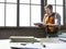 A businessman stands near the window and reads financial report.