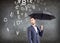 Businessman stands with umbrella under falling letters.