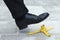 Businessman stepping on banana skin, business work accident danger concept