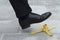 Businessman stepping on banana skin in street, banana peel accident