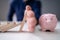 Businessman Stopping Domino Pieces Falling Towards Piggy Bank