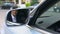 Businessman straightening shirt, ready for meeting, reflection in wing mirror