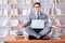 Businessman student in lotus position meditating with a laptop i