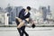 Businessman in suit and attractive sexy woman making dance of passion tango on the rooftop with skyscraper city view, have a crush