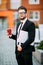 Businessman in suit with coffee in the hand walking with laptop in city street