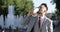 A businessman in a suit is drinking coffee against the background of fountains in the city.