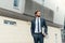 Businessman in suit with laptop in his hand goes to work on the road to the entrance of a glass office building