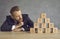 Businessman in suit looking at pyramid of cubes with question marks and thinking of answer