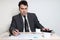 Businessman in suit looks at documents at table with coffee,