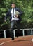 Businessman in suit and necktie carrying folder running desperate in stress on athletic track