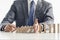 Businessman in a suit protecting wooden blocks from falling in a domino effect