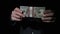 Businessman in Suit Shows Stack of 10000 American Dollars on Black Background