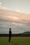 Businessman in a suit standing in green meadow under a glowing evening sky