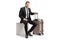 Businessman with a suitcase sitting on a white cube and looking at the camera