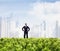 Businessman in sunglasses and hands on hips standing in a green field with city skyline in the background