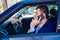 Businessman talking on his phone while driving his city car in the traffic jam