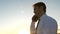 Businessman talking on a smartphone against the sky. man in a tie with a tablet in the park at sunset. talking mobile