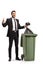 Businessman throwing a waste bag in a garbage bin and holding thumbs up