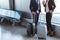 businessman with tickets and businesswoman with coffee to go standing near window at departure lounge