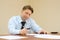 Businessman in tie sits at table and signs documents