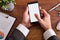 Businessman touching a smartphone on wood table top