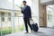 Businessman with trolley bag using mobile phone