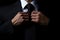 Businessman tying his necktie on black background, close-up