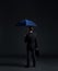 Businessman with umbrella. Black background with copyspace.