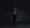 Businessman with umbrella standing under the rain. Dark, dramatic background. Business, failure, crisis, concept.