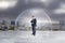 Businessman under glass cover standing on gloomy city background.