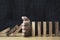 à¸ºBusinessman uses his hand to stop a falling wooden block to a standing wooden block domino , It is a symbol of protection