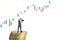 Businessman using binoculars standing above coin stack, with bullish growth increase candle stick chart. Miniature tiny people