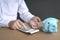 Businessman using calculator with empty piggybank and a coin left on table