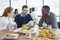 Businessman using digital table while sitting with colleagues in cafeteria