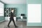 Businessman walking in modern blue office interior with empty mock up poster on wall, bookcase, window with city view, workplace