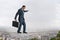 Businessman walking tightrope above city