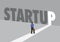 Businessman walking towards a light path with the text startup. Business concept of corporate success, innovation or overcoming